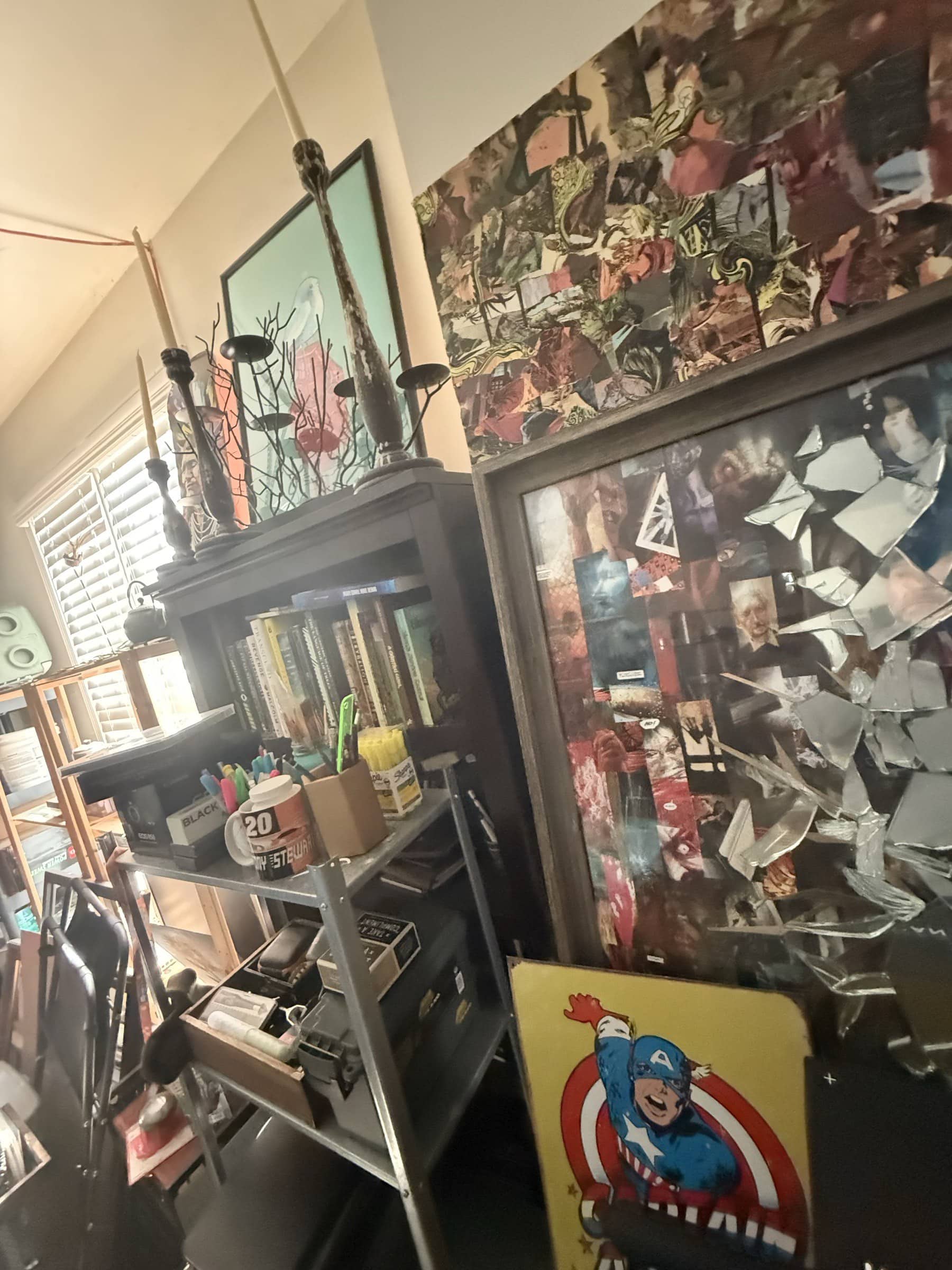 Angled view of the garage environment with framed works, shelving, and the Captain America panel near the wall.