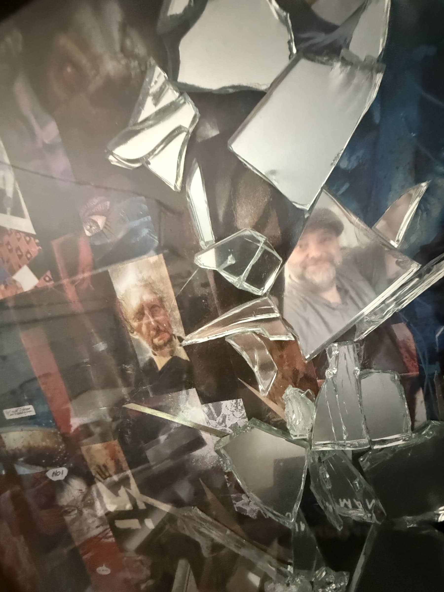 Broken mirrored fragments reflecting the operator inside a framed collage surface.